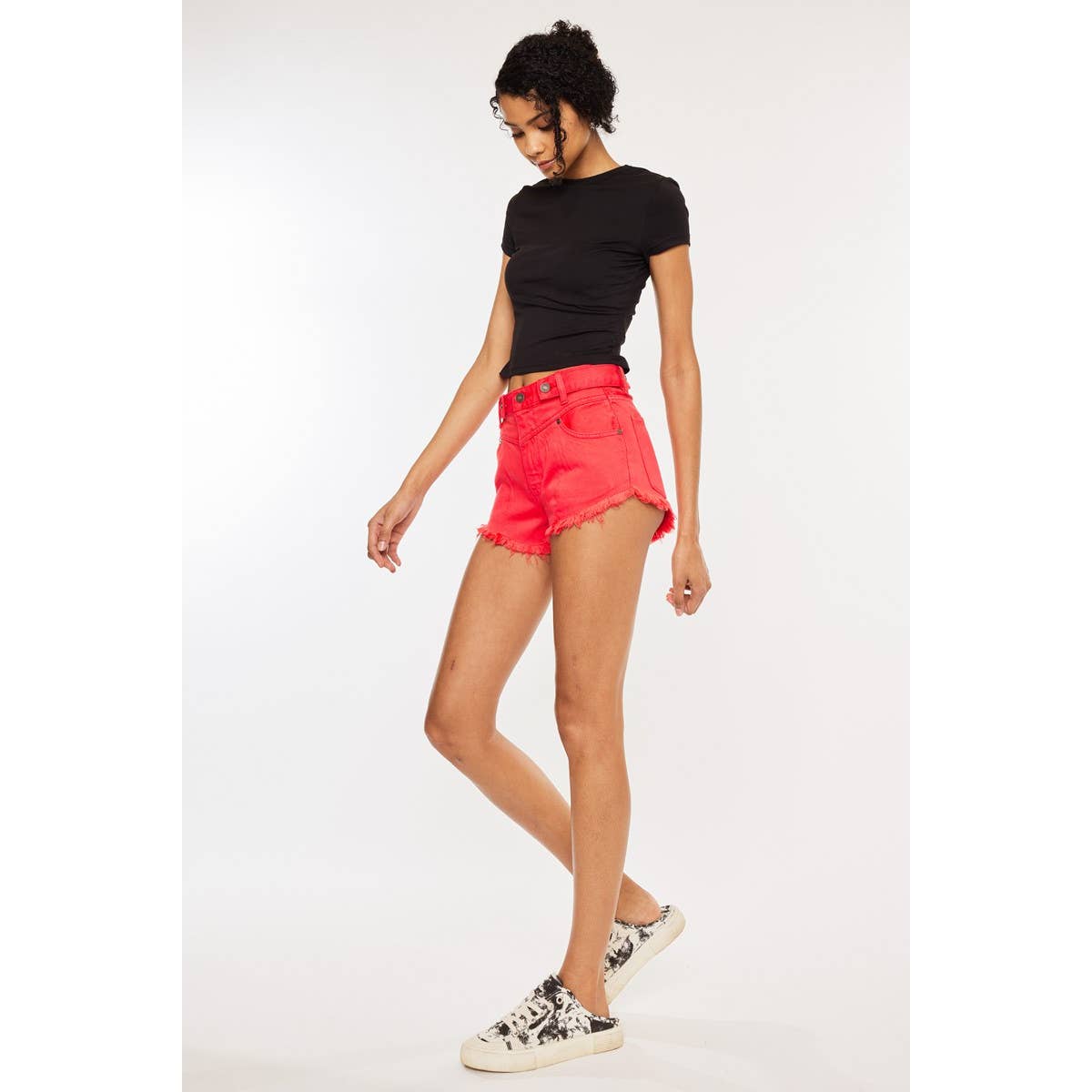 zoomed out side view of Kan Can USA high rise coral red shorts with frayed hem and button accent