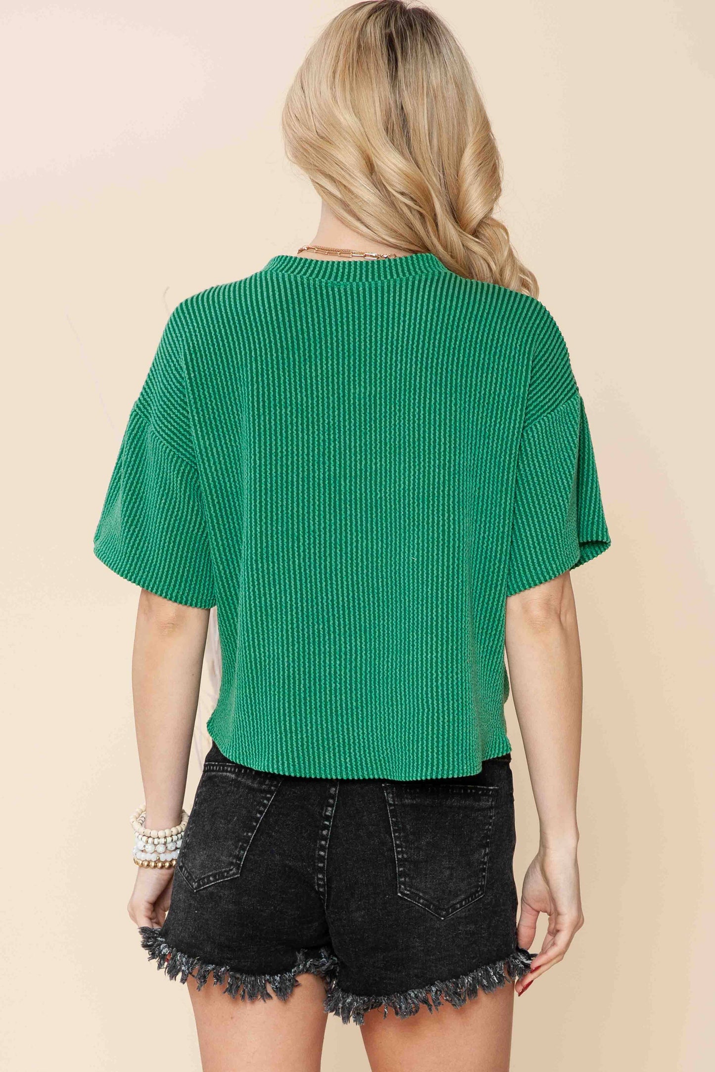 back view of Sage wave rib short sleeve crop top with a front tie and pocket, made from supersoft material, offering a loose fit and vibrant look.
