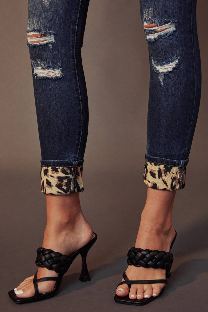 hem detail of Kan Can Mid Rise Leopard Patch Super Skinny Jeans in Dark Wash with leopard patch details, 5-pocket design, and a zip fly. Features an 8.5" rise and 29.5" inseam (before folding), made from a blend of cotton, polyester, rayon, and Lycra.