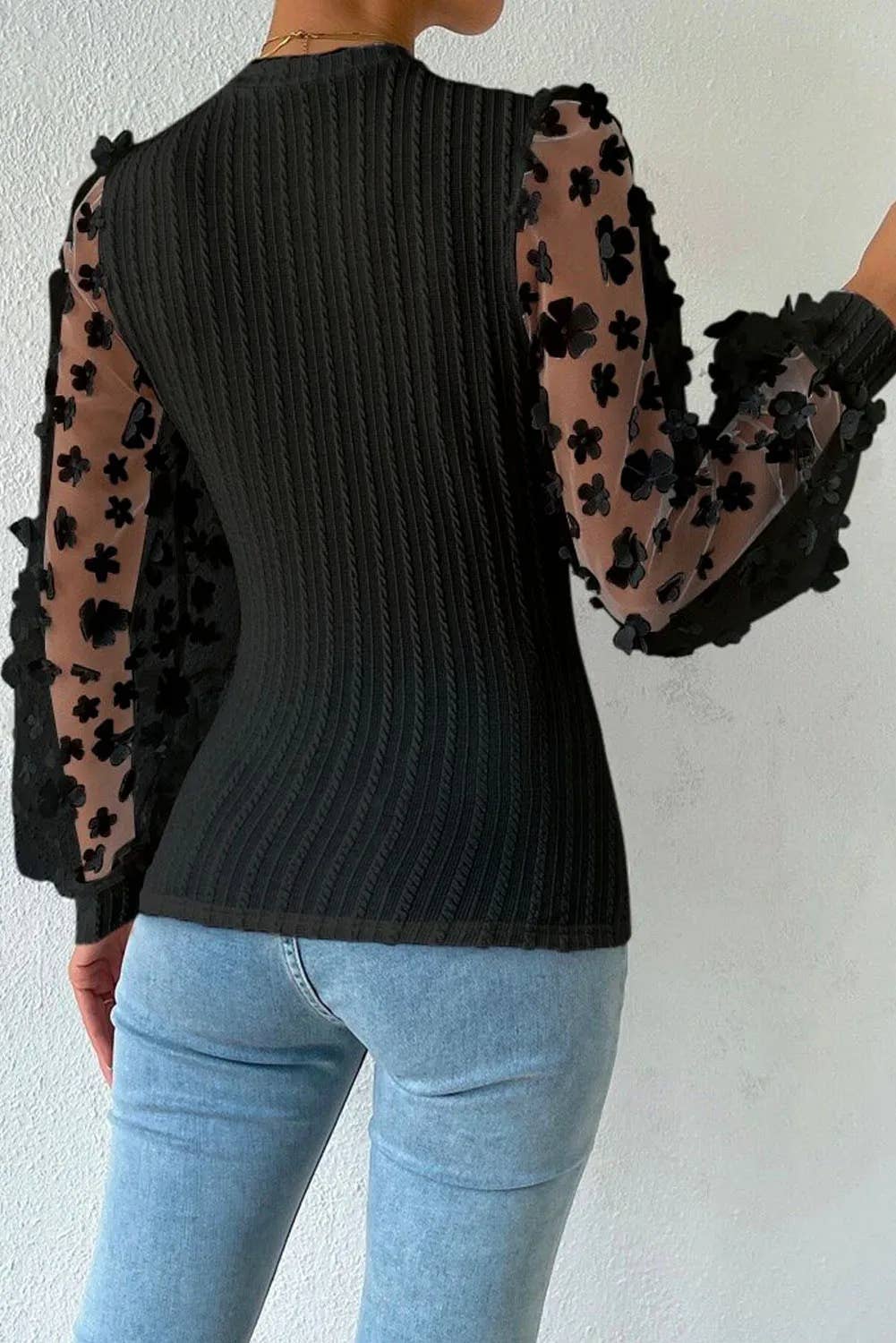 back view of black Textured knit blouse with floral applique mesh sleeves, crew neck, and elegant detailing for a chic and sophisticated look.