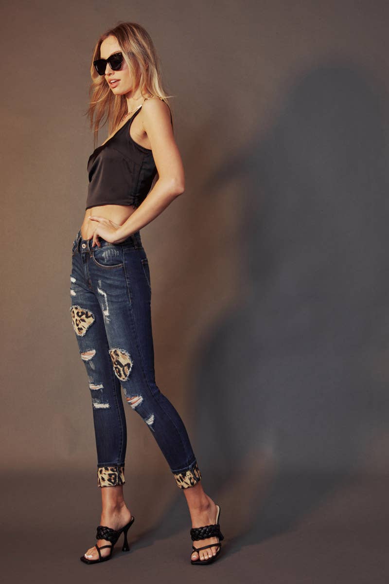 side view of Kan Can Mid Rise Leopard Patch Super Skinny Jeans in Dark Wash with leopard patch details, 5-pocket design, and a zip fly. Features an 8.5" rise and 29.5" inseam (before folding), made from a blend of cotton, polyester, rayon, and Lycra.