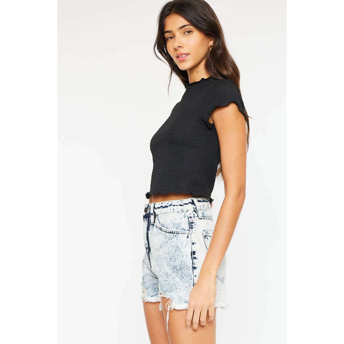 slight side view of Kan Can USA High Rise Mom Denim Shorts in Acid Wash with a frayed hem, distressed details, and rigid fabric. Featuring an 11.5" rise and 2.5" inseam, made from 100% cotton.