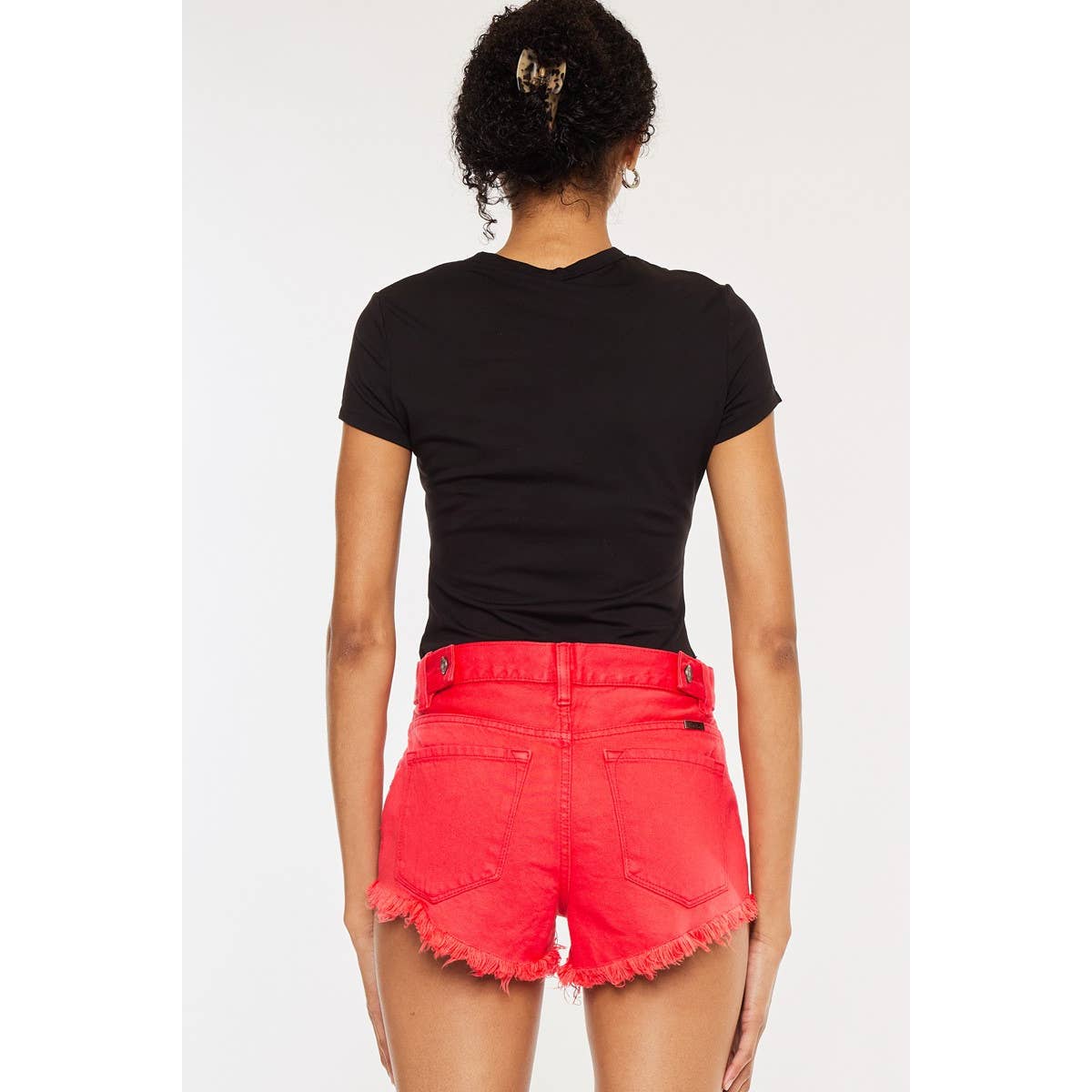 back view of Kan Can USA high rise coral red shorts with frayed hem and button accent