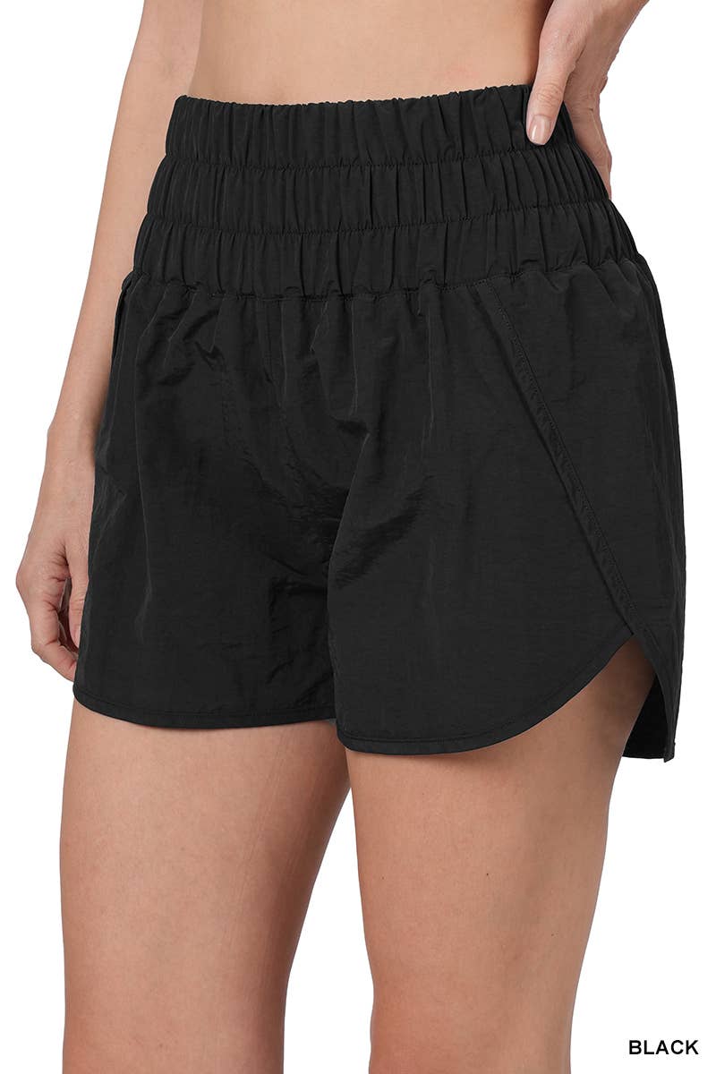 modeling wearing Black Smocked Waistband Running Shorts with a mesh waist pocket, split hem, and built-in inner brief. Made from 100% nylon shell and 96% polyester, 4% spandex lining. Relaxed fit with a total waist of 27" and inseam of 2 3/8".