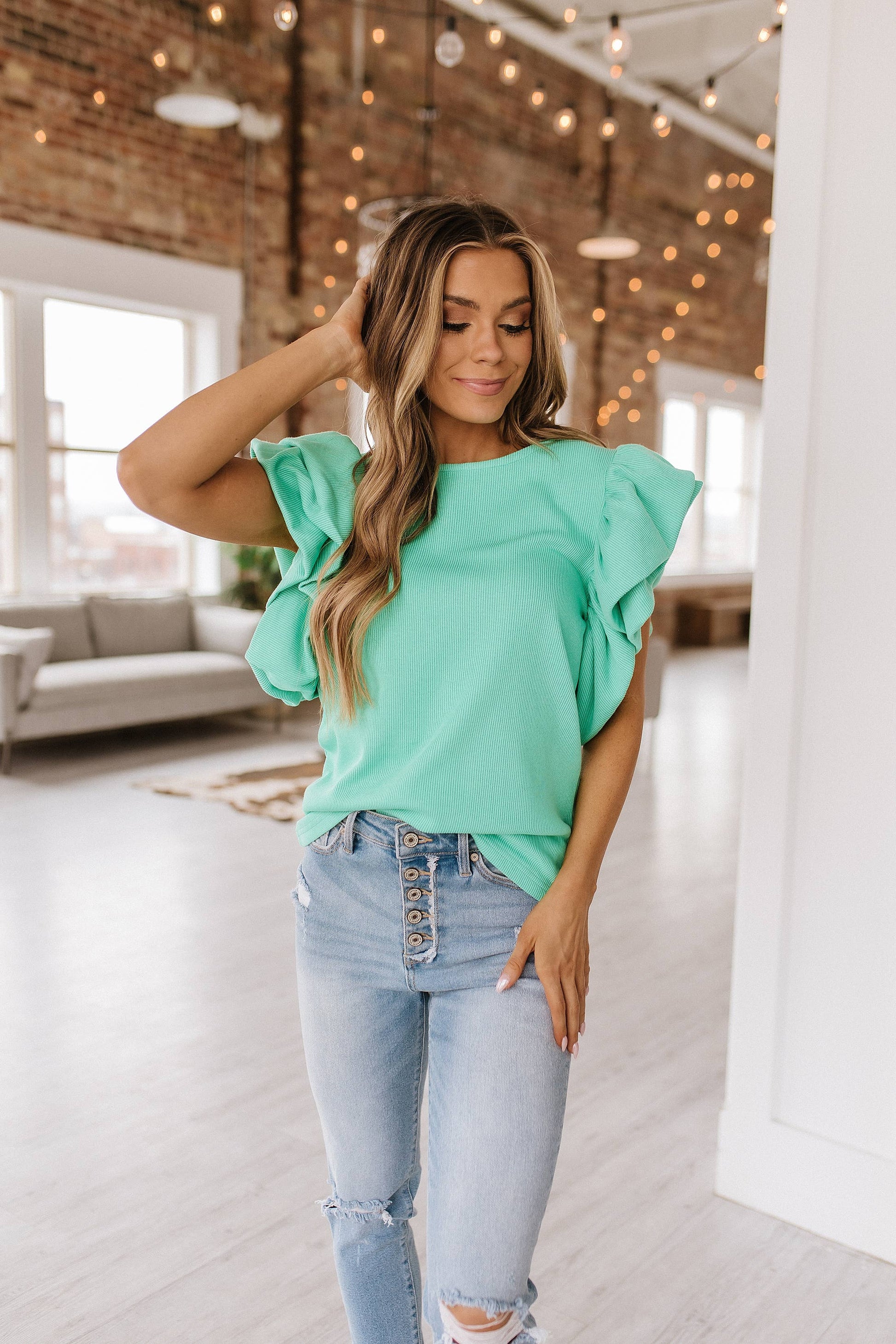 styled view of Aurelia blouse featuring delicate ruffle sleeves, made from 65% cotton, 33% polyester, and 2% elastane, offering an elegant and comfortable look.