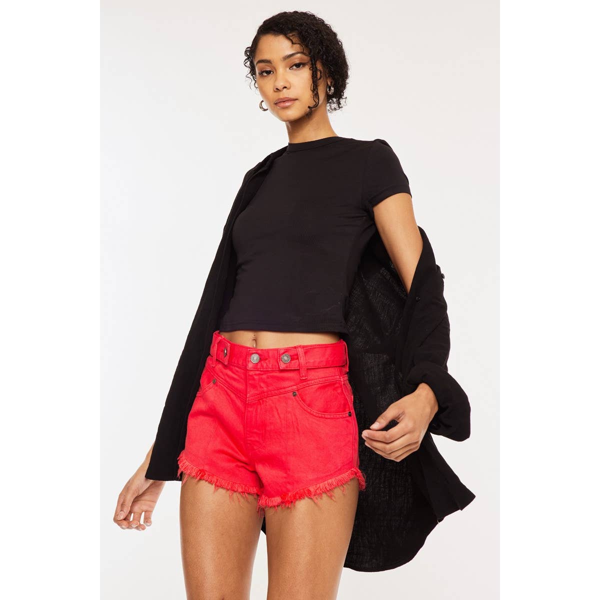 slight side view of Kan Can USA high rise coral red shorts with frayed hem and button accent