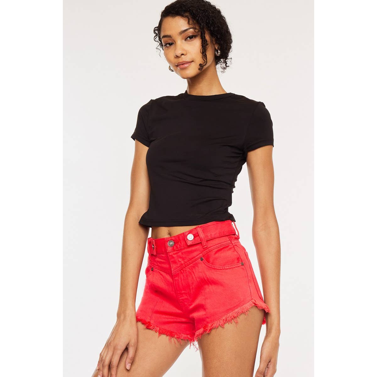 slight side view of Kan Can USA high rise coral red shorts with frayed hem and button accent