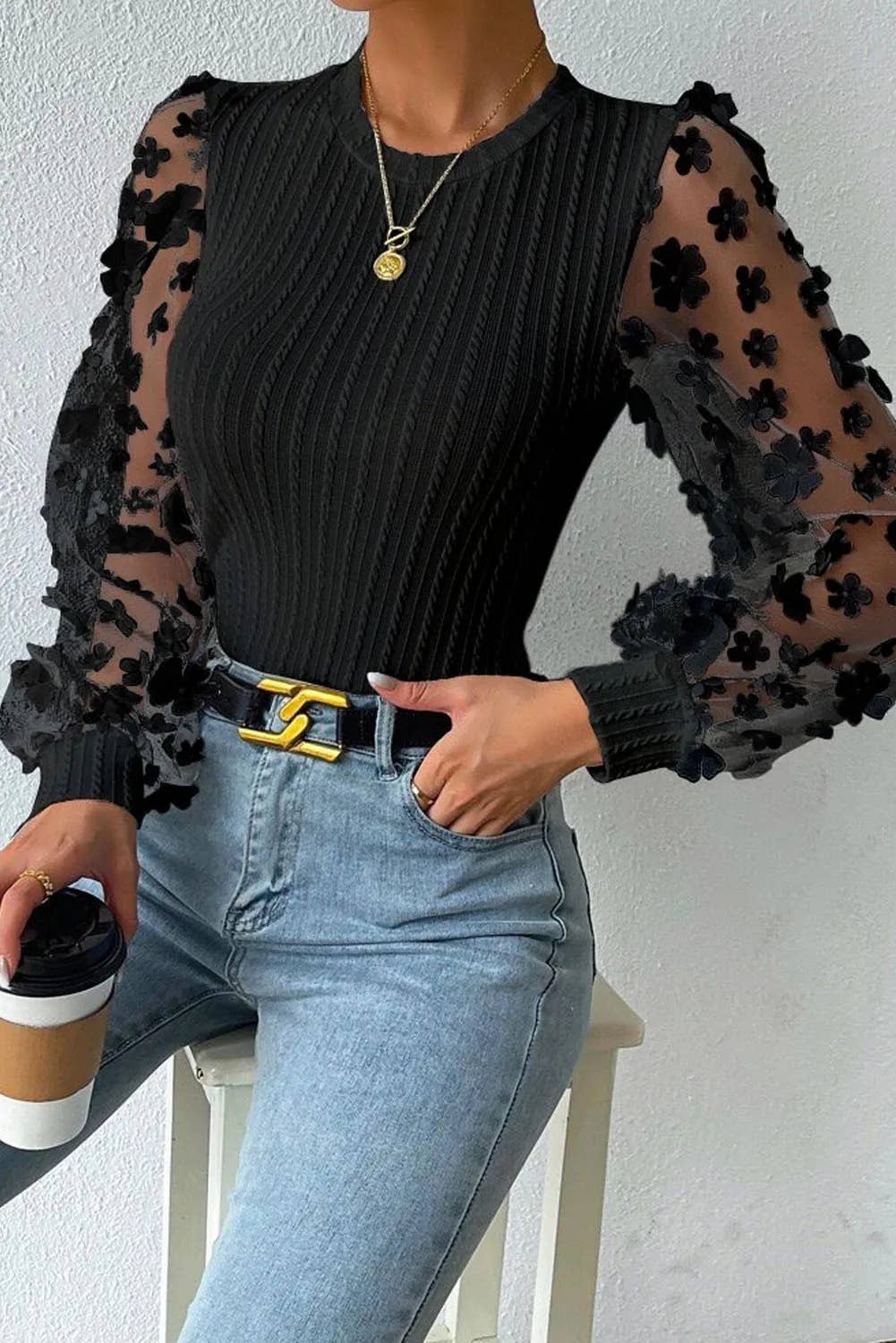 styled view of black Textured knit blouse with floral applique mesh sleeves, crew neck, and elegant detailing for a chic and sophisticated look.