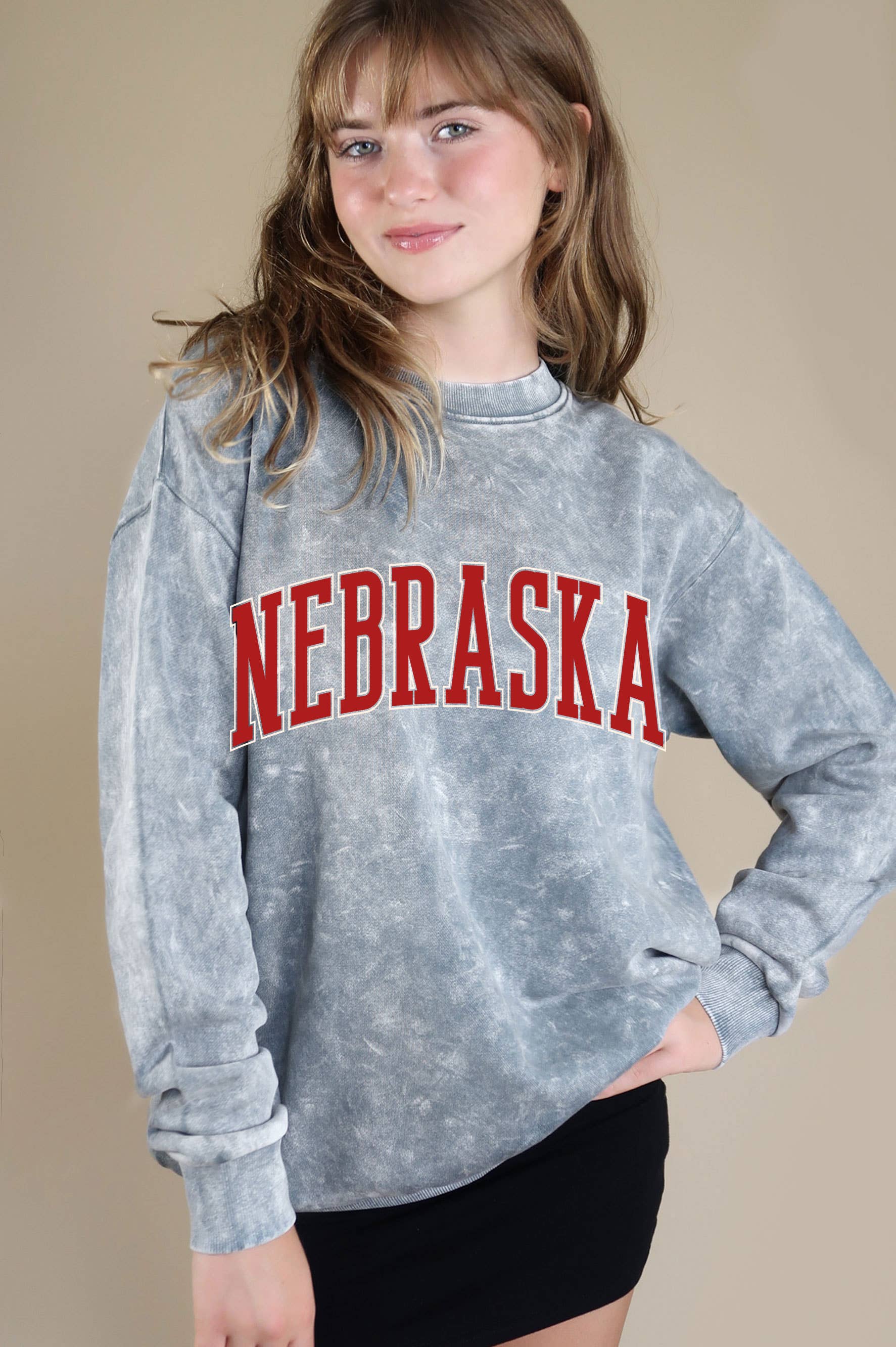 styled view of Grey Nebraska Puff Mineral Graphic Sweatshirt with a classic crew neckline, drop shoulder sleeves, and soft, cozy fabric. Features mineral dye variations.