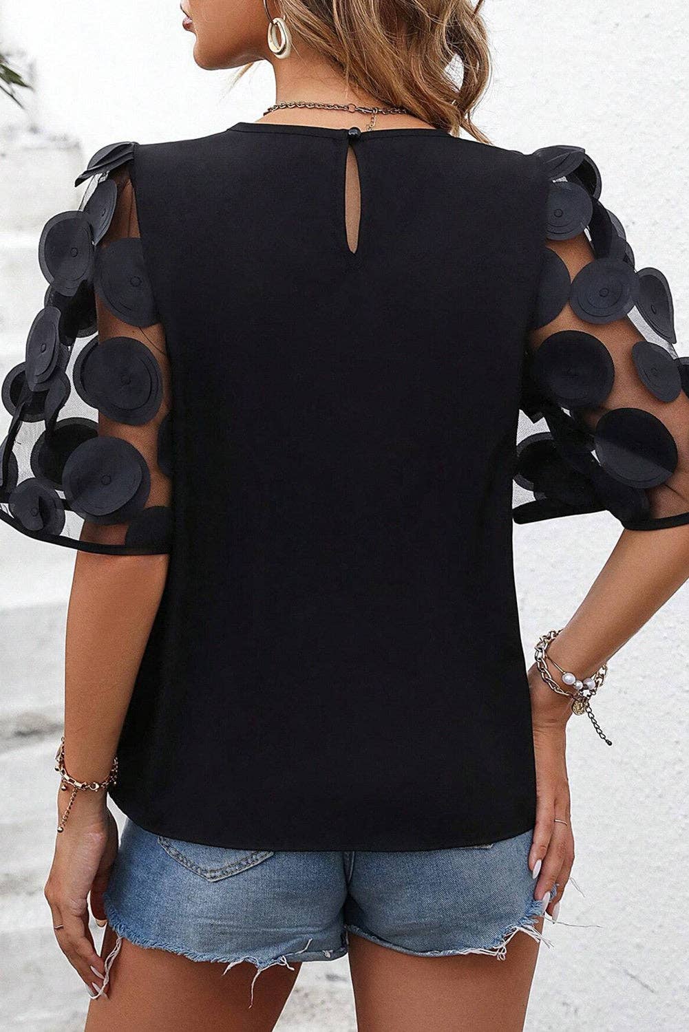 back view of Black blouse with contrast applique design and mesh half sleeves, offering a chic and edgy look that's both feminine and versatile.