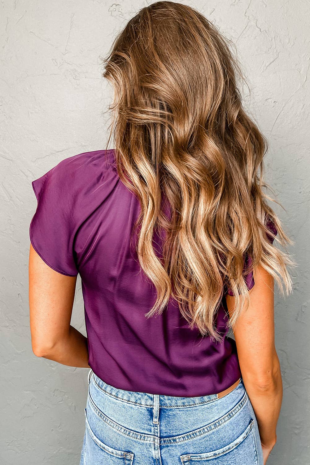back view of Elegant satin top with pleated detail and flutter sleeves, offering a sleek, luxurious look and versatile styling options.