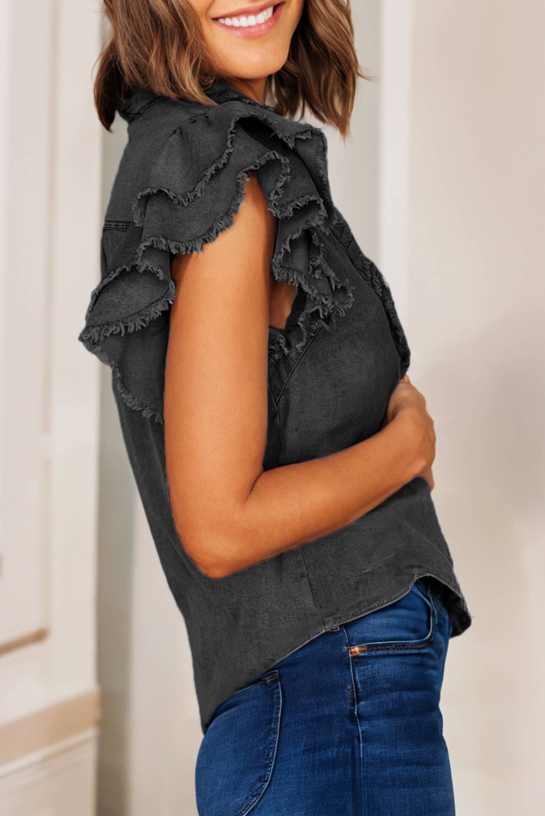 side view of black Button front denim blouse with ruffle and flutter sleeves, featuring a frayed hem for a casual and chic look.
