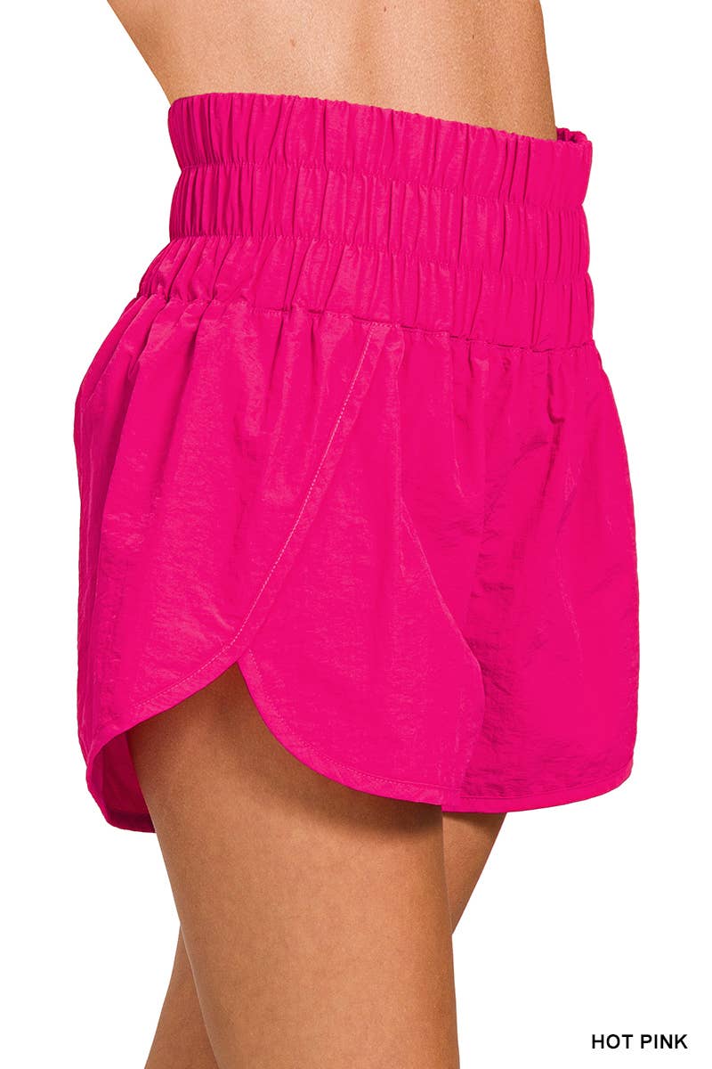 side view of Fuchsia Smocked Waistband Running Shorts with mesh waist pocket, split hem, and built-in inner brief. Made from 100% nylon shell and 96% polyester, 4% spandex lining, with a total waist of 27" and inseam of 2 3/8".