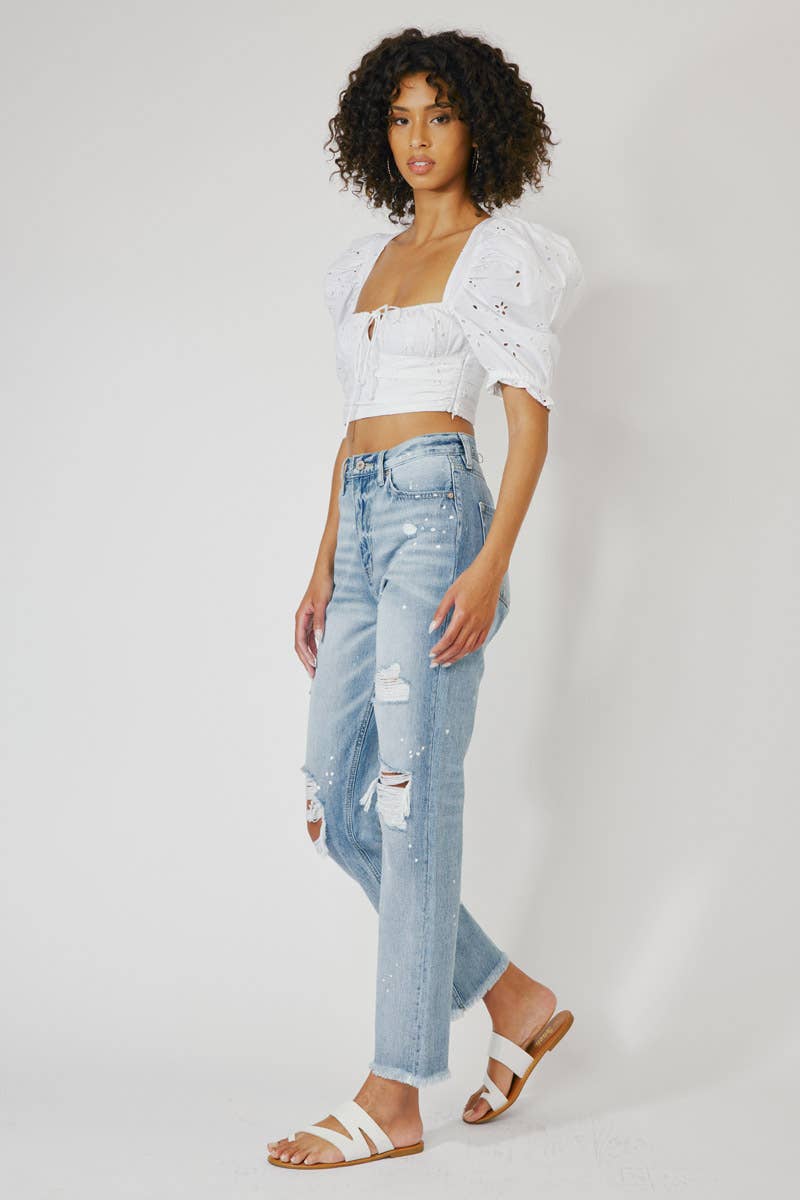 side view of High Rise Slim Straight Jeans in Medium Stone Wash, featuring a 12" rise, 28" inseam, rigid 100% cotton fabric, frayed hem, paint splatter accents, and distressed details with a zip fly.